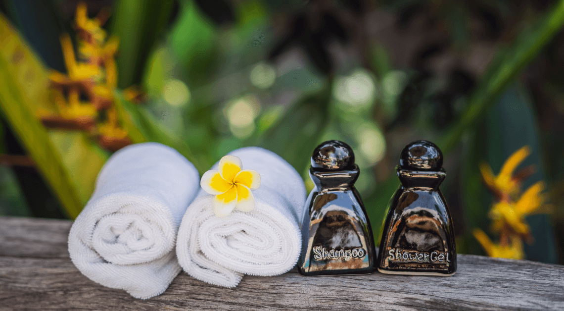 Freshly folded towels and premium shampoo bottles displayed as welcoming vacation rental amenities. Ask ChatGPT